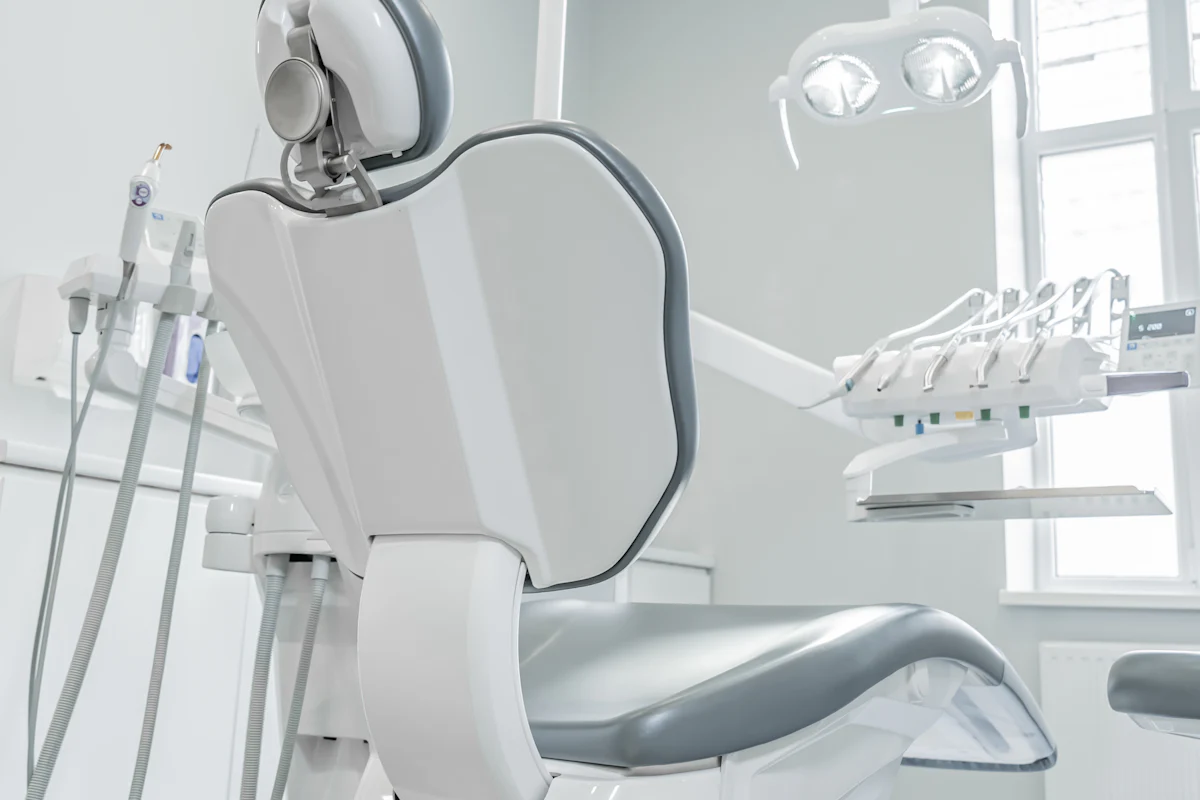 Cadeira odontológica branca ao lado de uma janela